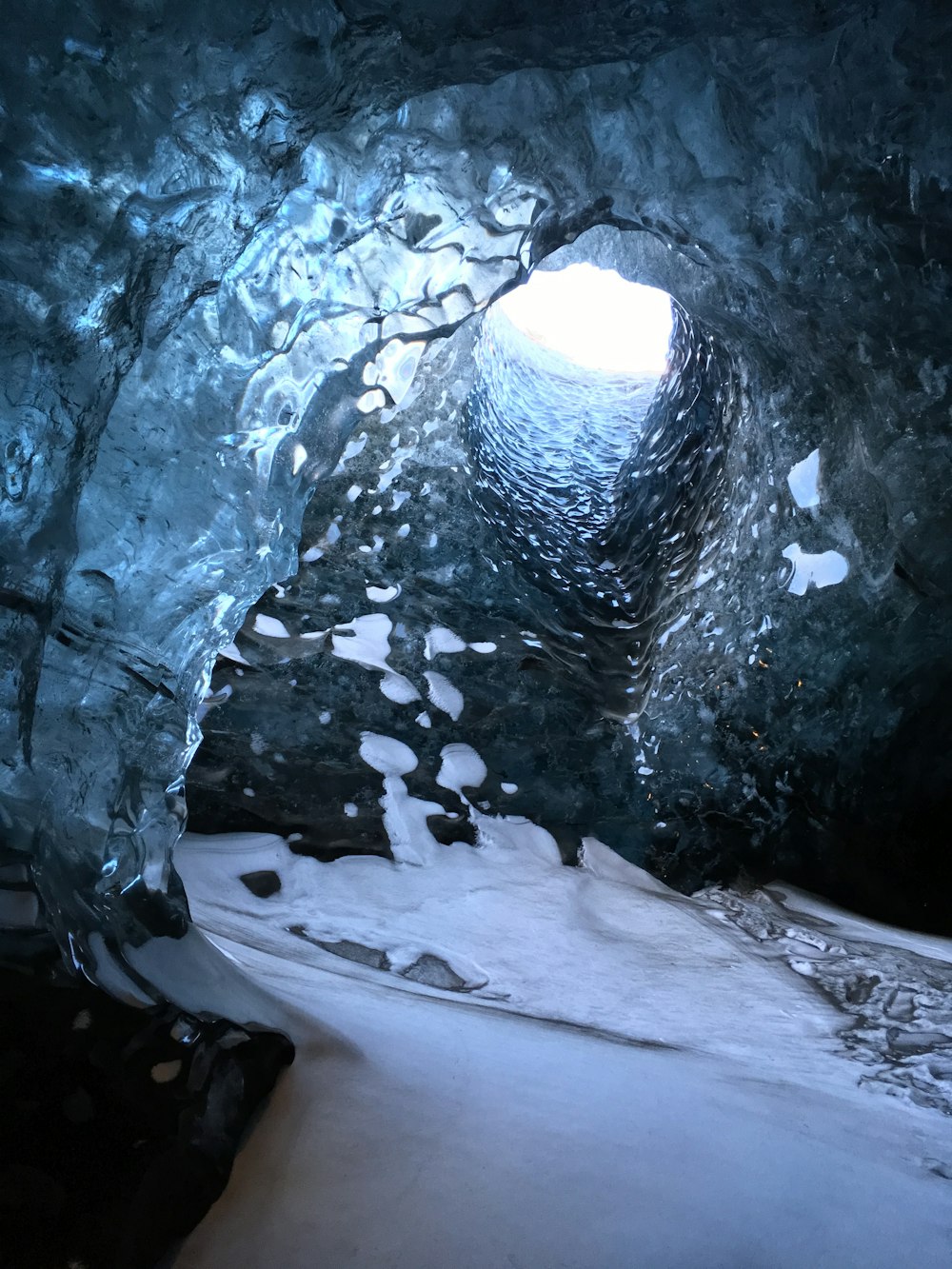 a large ice cave with snow on the ground