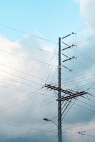 a pole with many wires and a traffic light on top of it