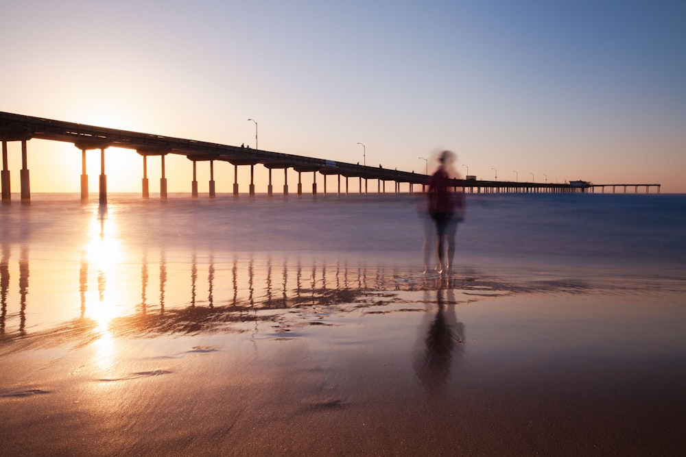 a person standing on a beach at sunset