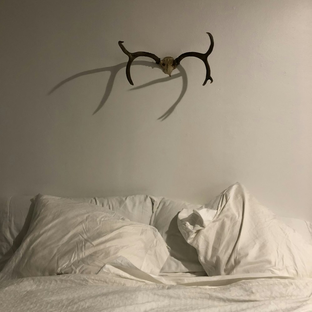 an antelope head hangs on the wall above a bed