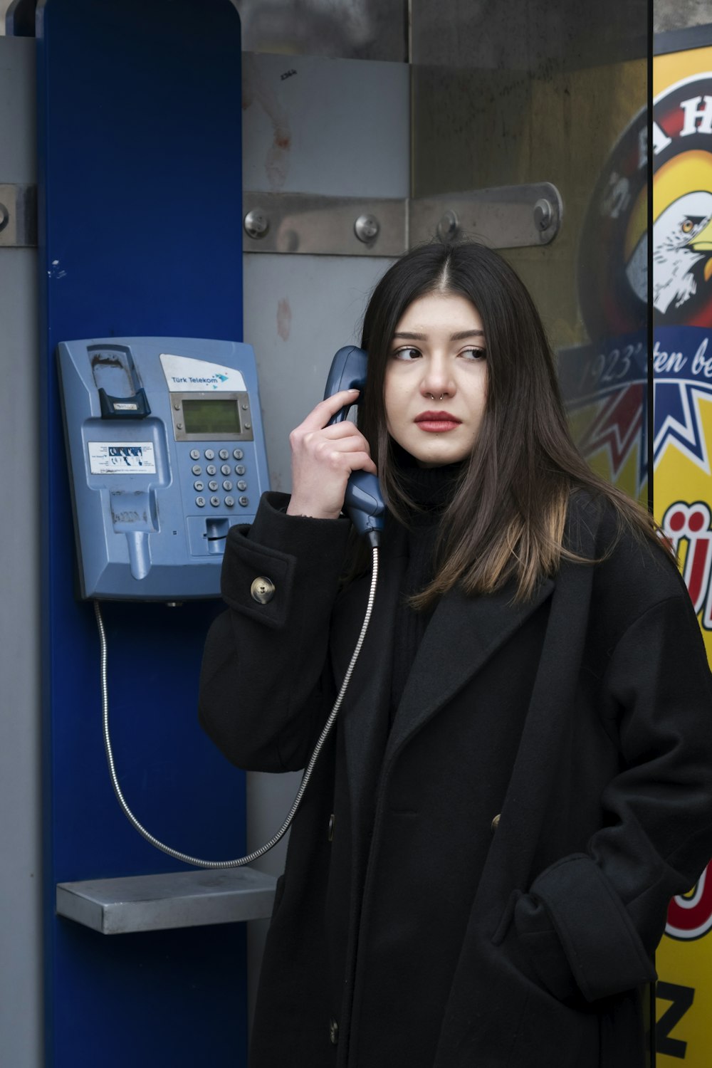 a woman standing in front of a pay phone