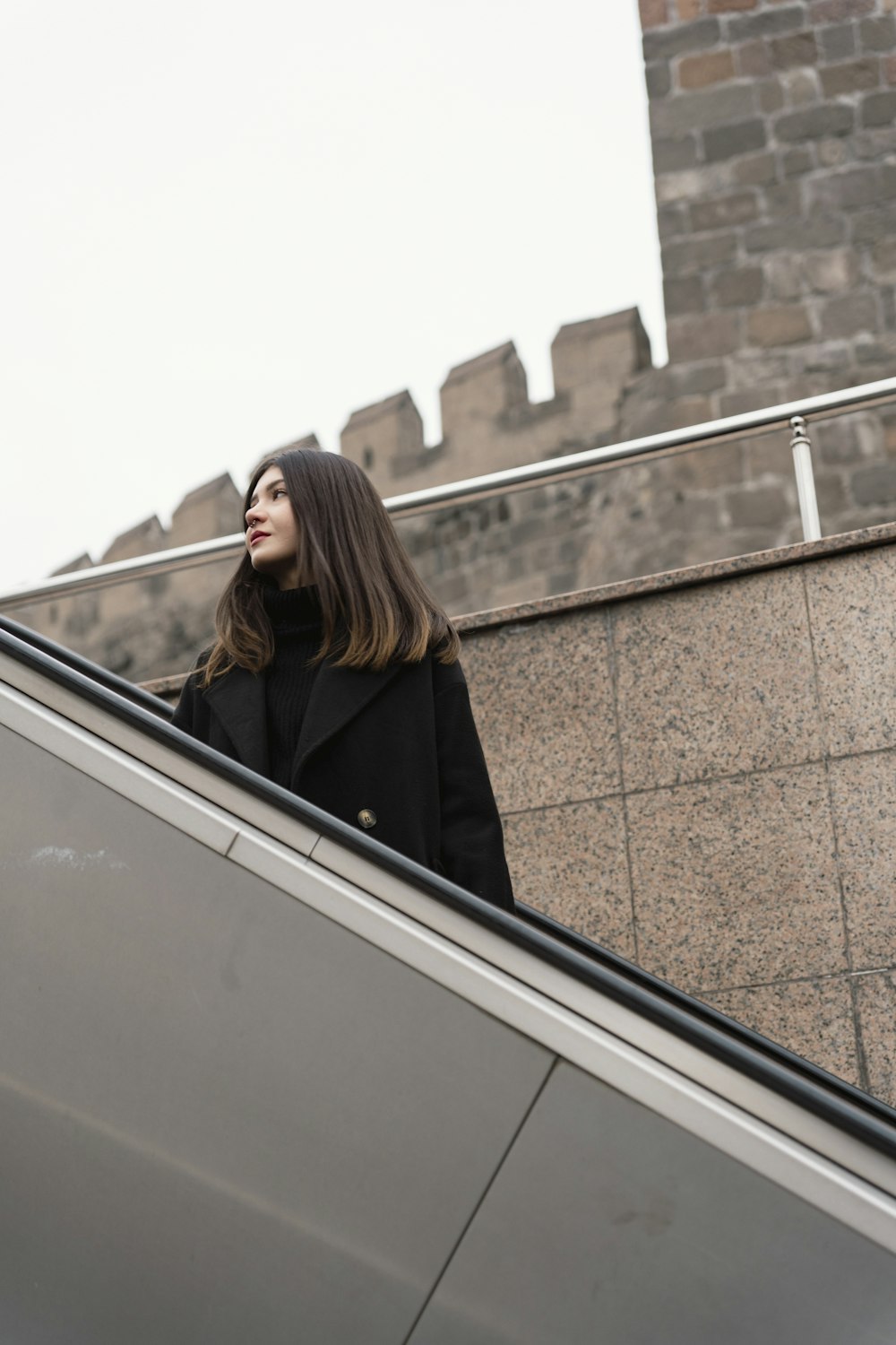 a woman standing on an escalator next to a building