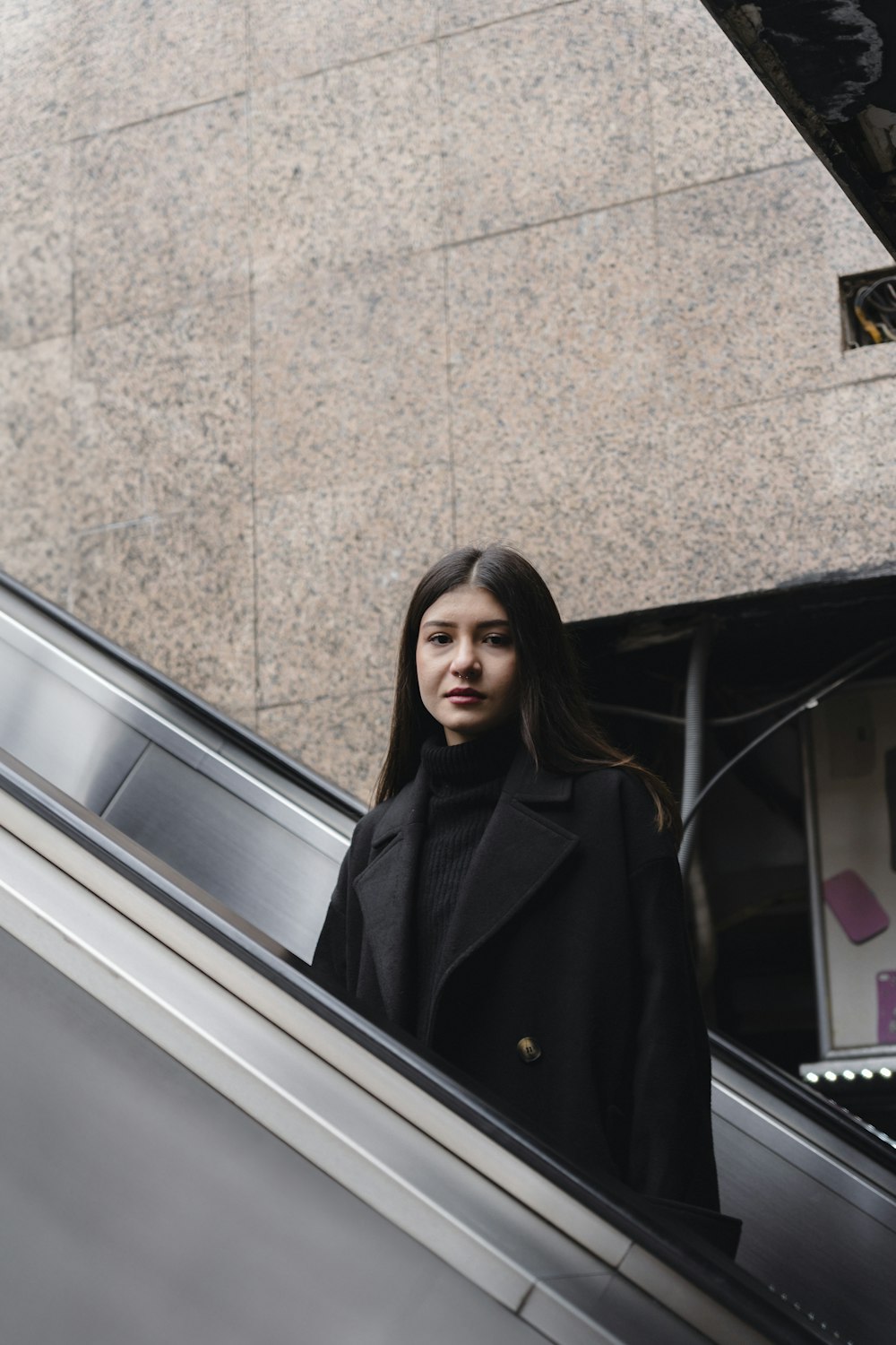 a woman standing on an escalator next to an escalator