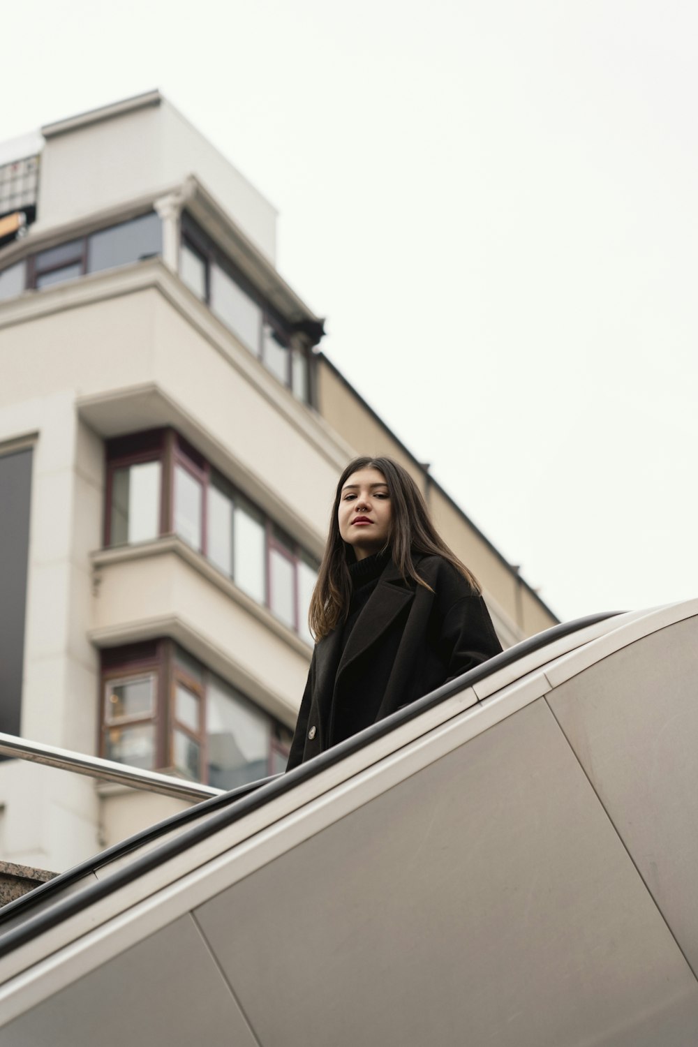 a woman is standing on an escalator in front of a building