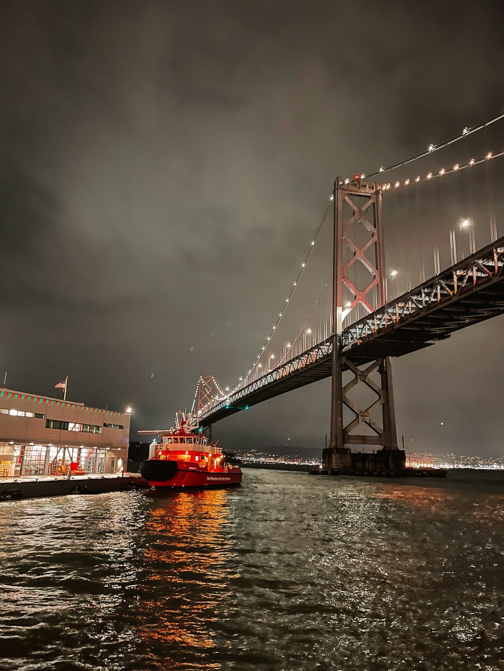 a large boat floating under a bridge at night