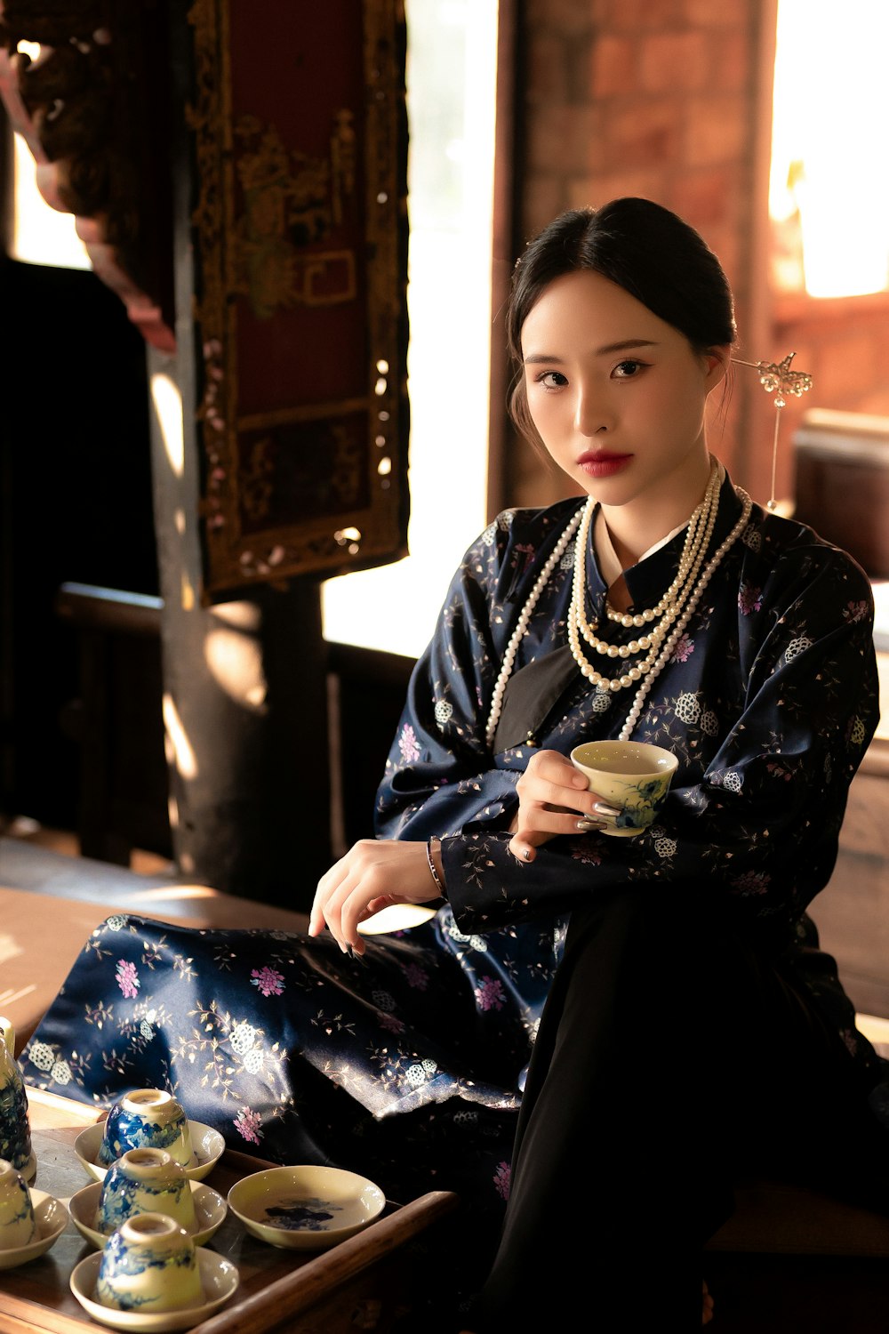 a woman sitting on the floor with a tray of tea cups