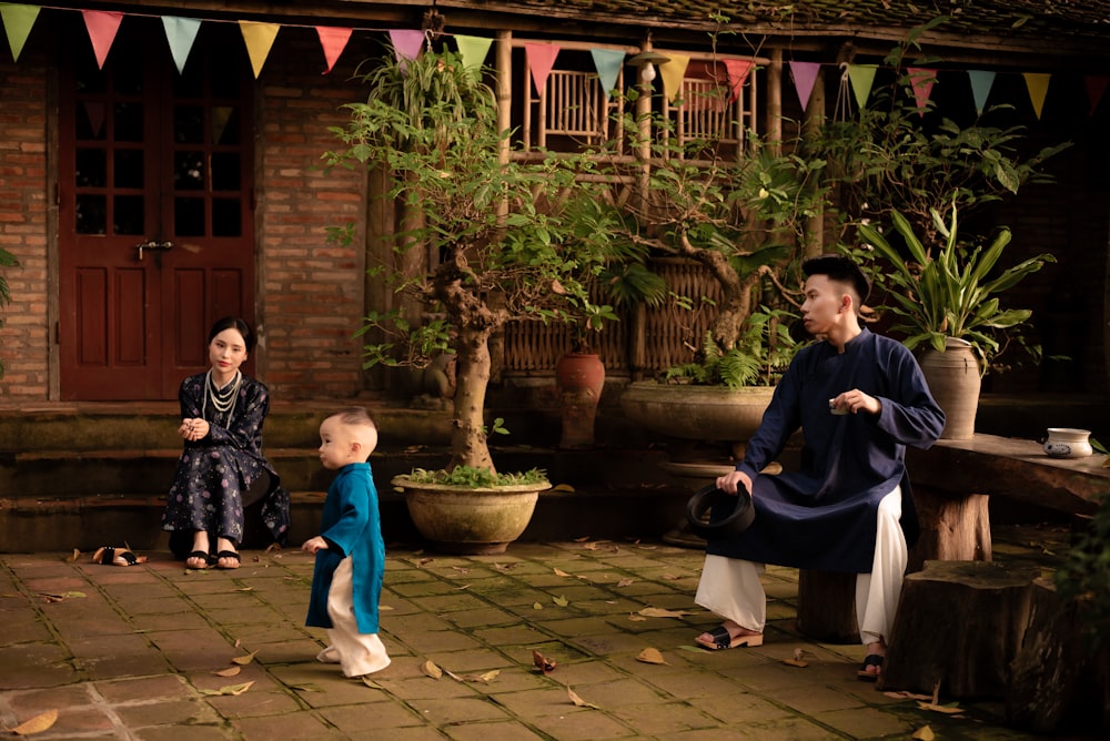 a man and a woman sitting on a bench next to a little boy