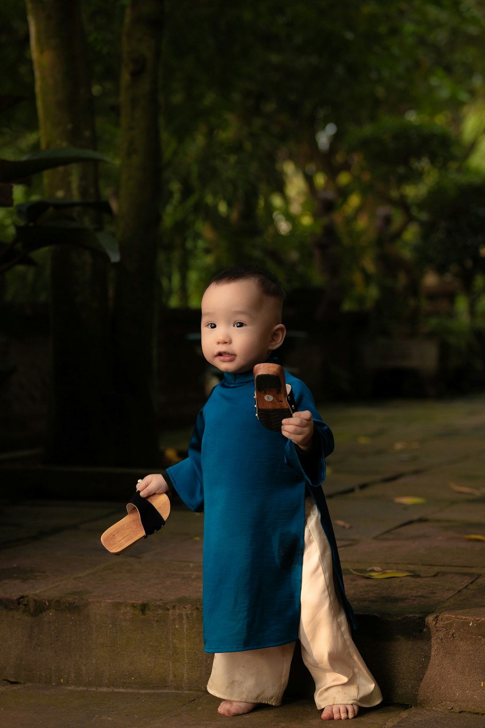 a little boy holding a cell phone and wearing a blue shirt