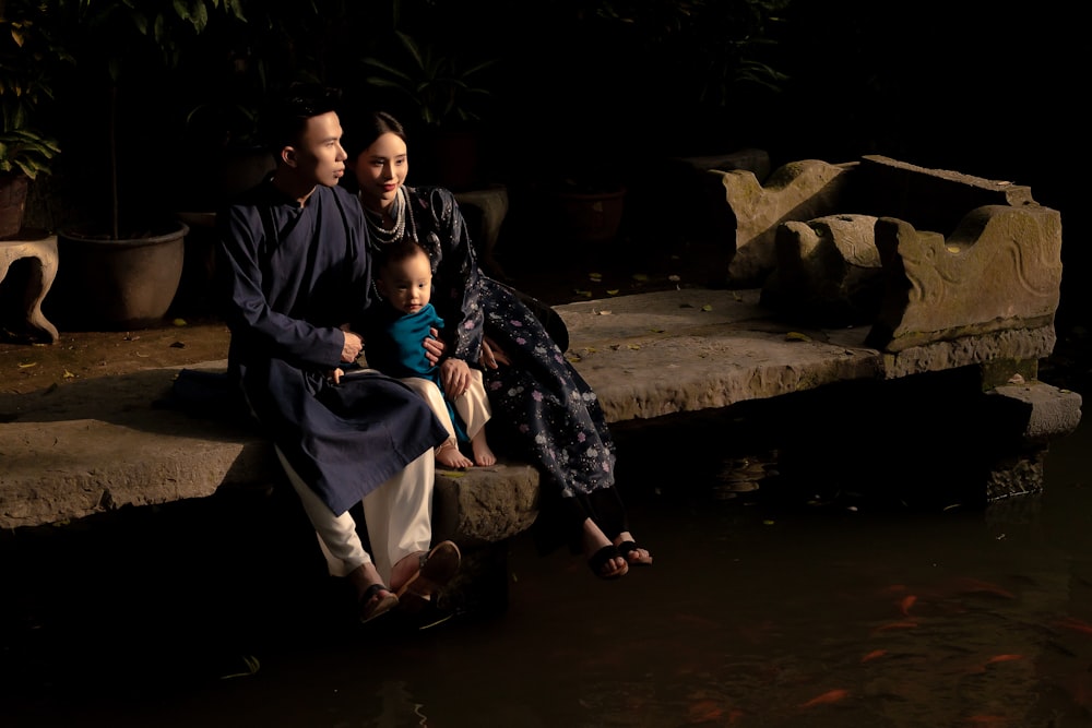 a family sitting on a stone bench in the water