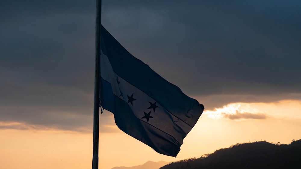 a flag flying in the wind with a mountain in the background