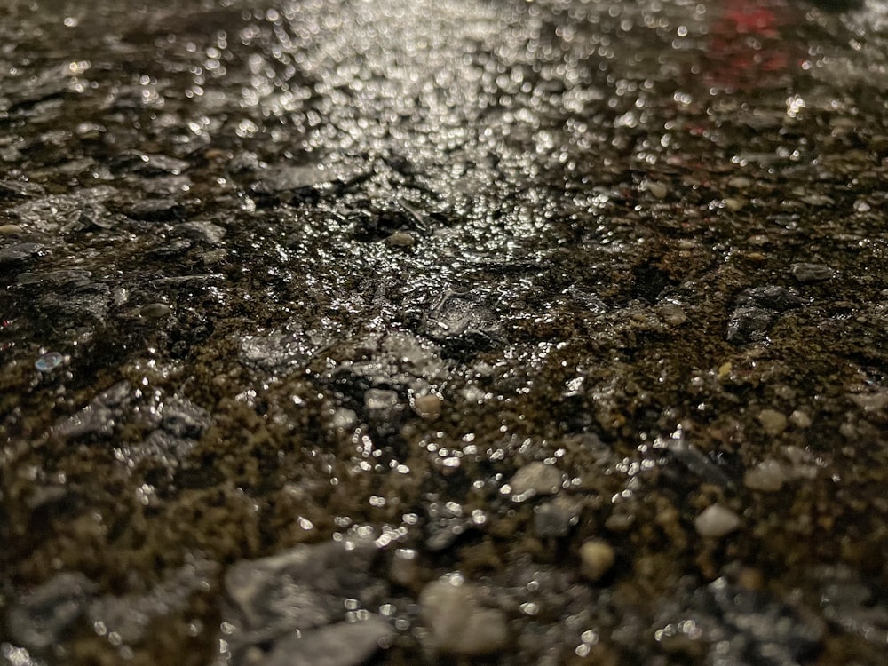 a close up of a wet surface with a red object in the background