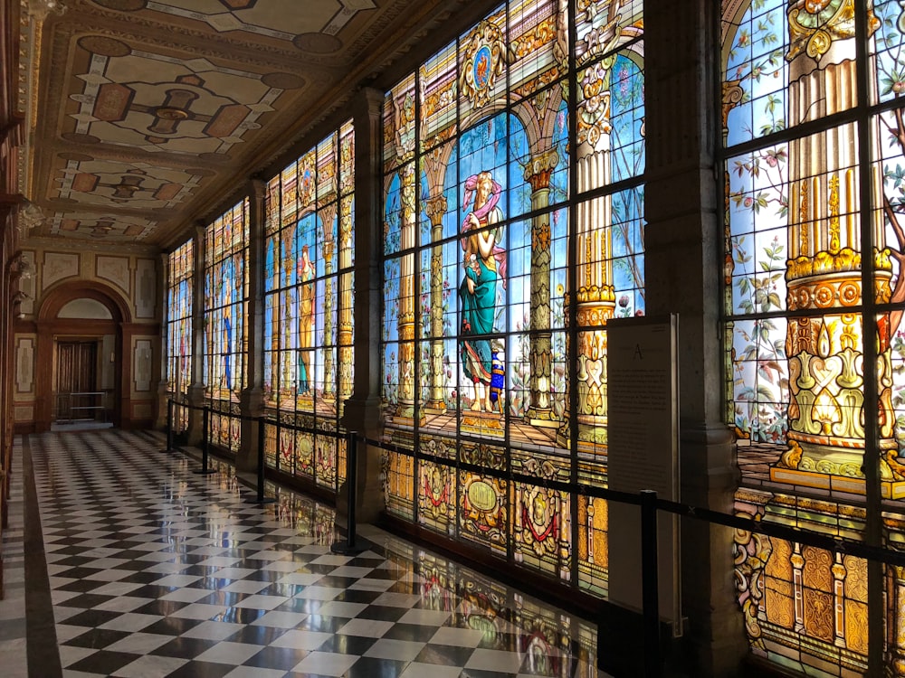 a hallway with a checkered floor and large stained glass windows