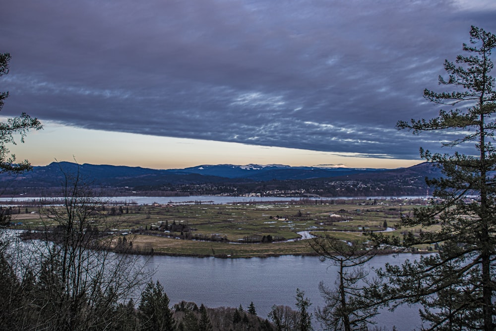 a view of a lake and mountains from a hill