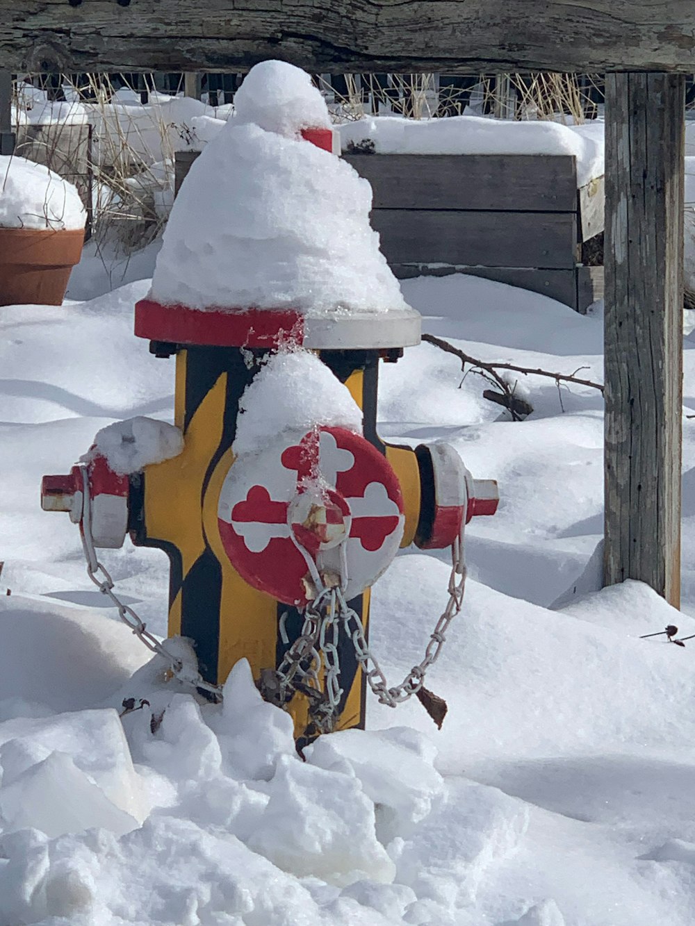 a fire hydrant covered in snow next to a bench