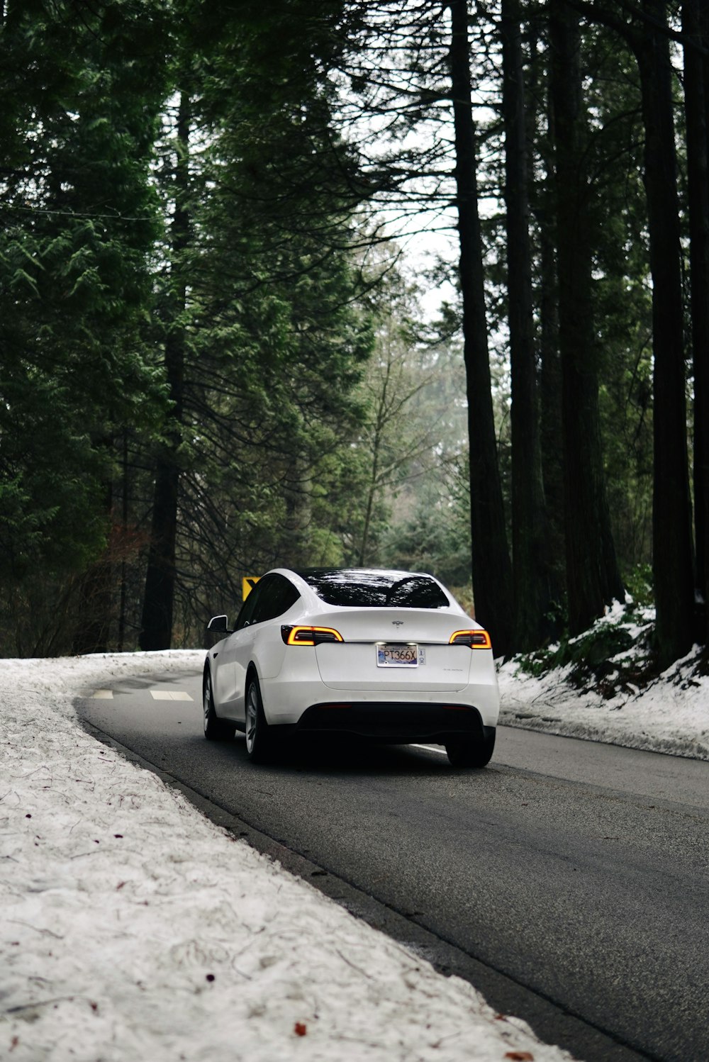 Un coche blanco conduciendo por una carretera cubierta de nieve