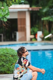 a man sitting on the edge of a swimming pool