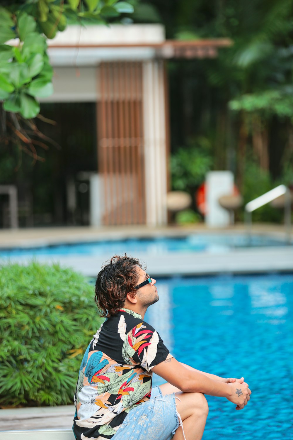 a man sitting on the edge of a swimming pool