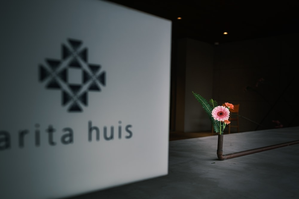 a flower in a vase sitting in front of a sign