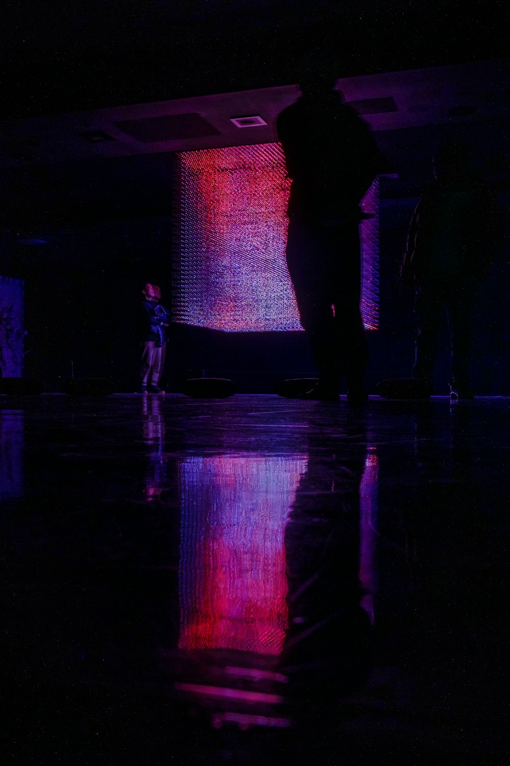 a person standing in a dark room with a reflection on the floor
