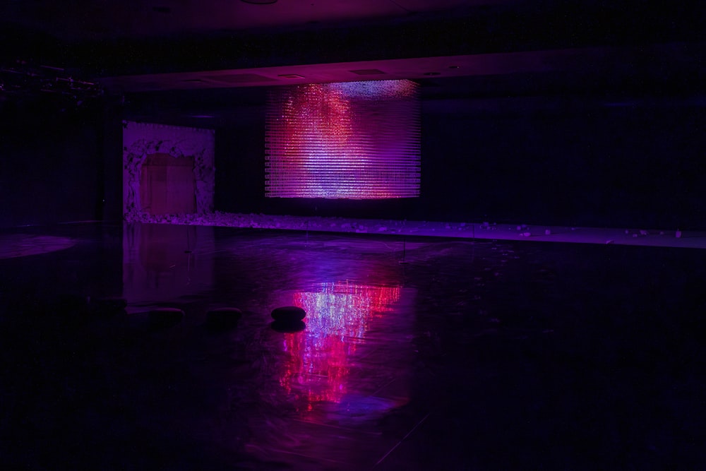 a dark room with a purple light reflecting off of the floor
