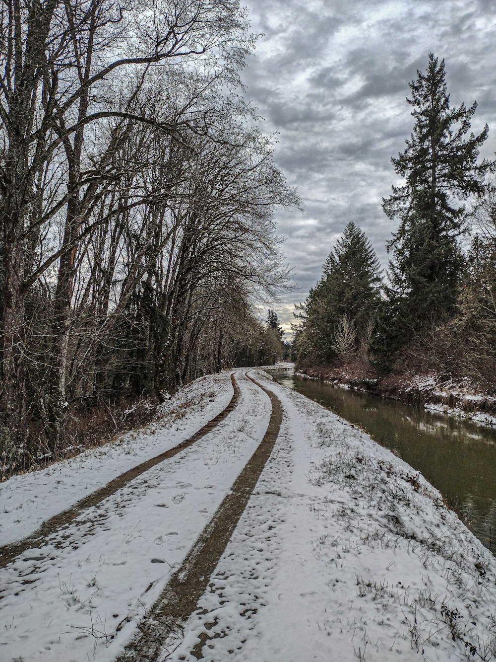 a snow covered road next to a river