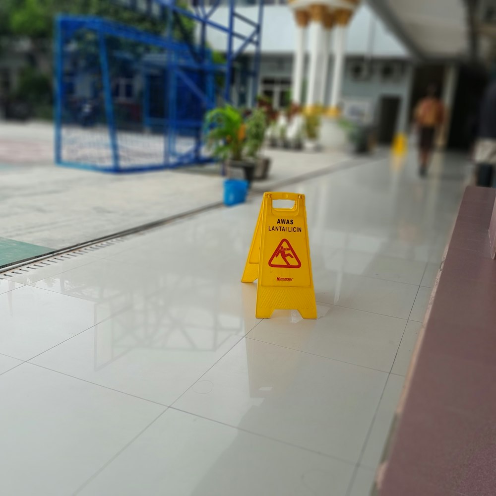 a yellow caution sign sitting on top of a white floor