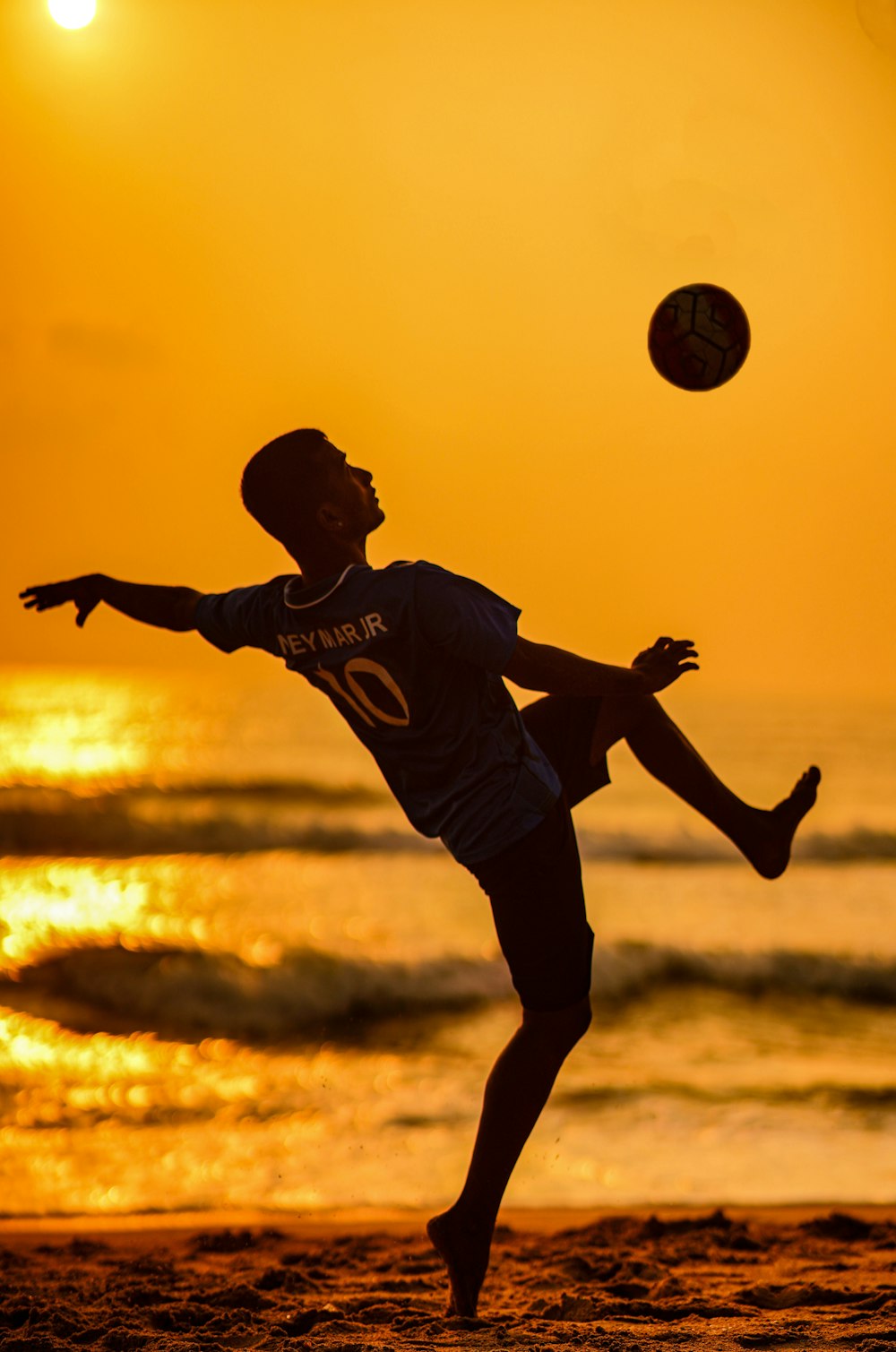 a man is playing with a ball on the beach