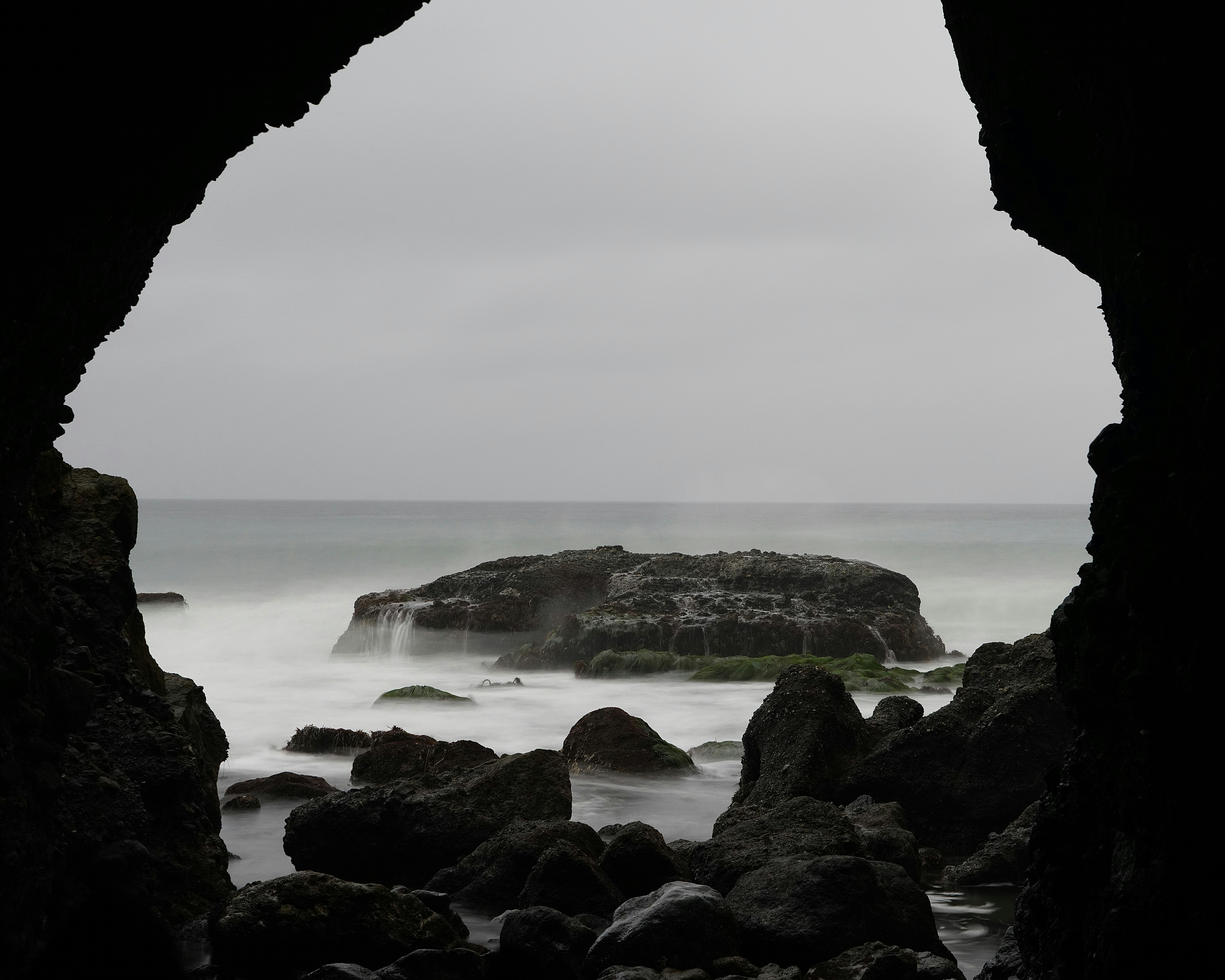 a view of a body of water through a cave, 