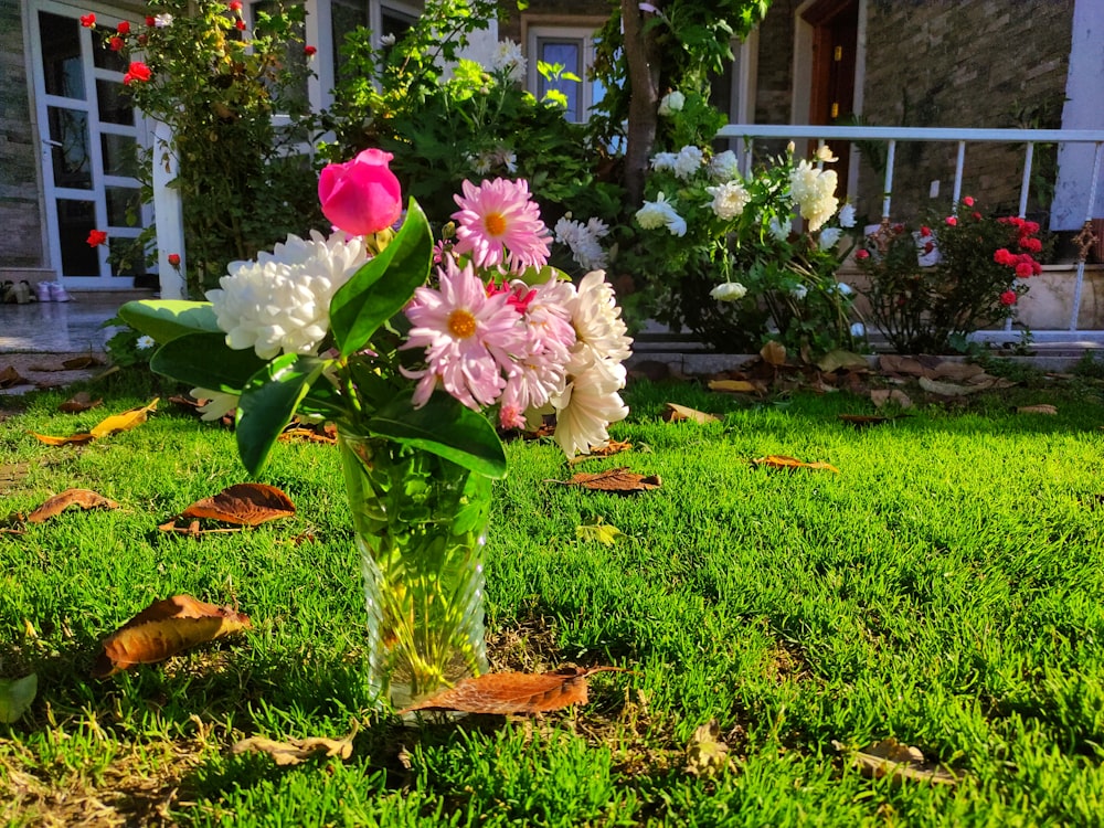 a vase filled with flowers sitting on top of a lush green field