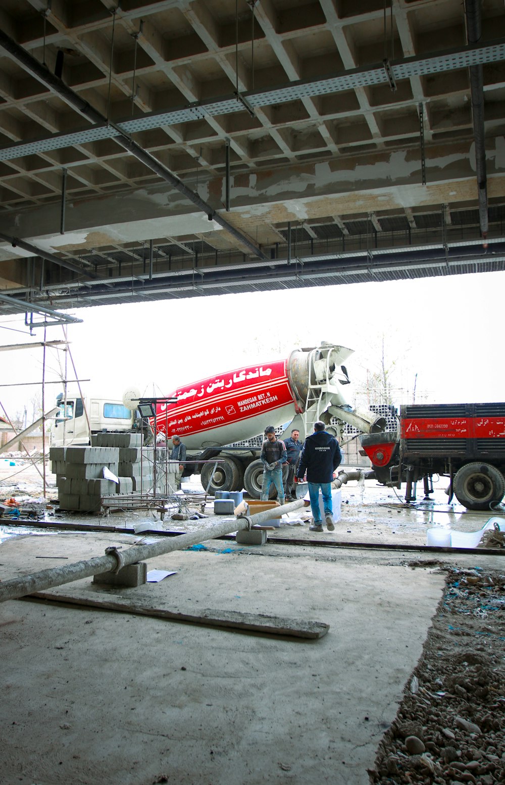 a cement mixer being worked on under a bridge