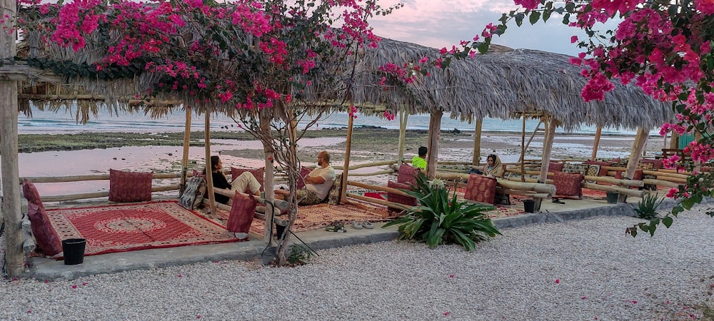 a group of people sitting under a thatched umbrella