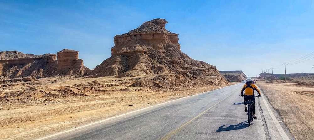 a man riding a bike down a desert road