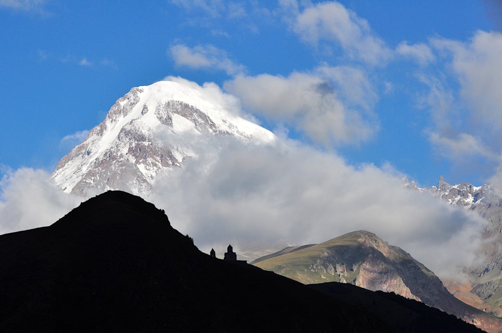 a snow covered mountain in the distance with clouds in the sky