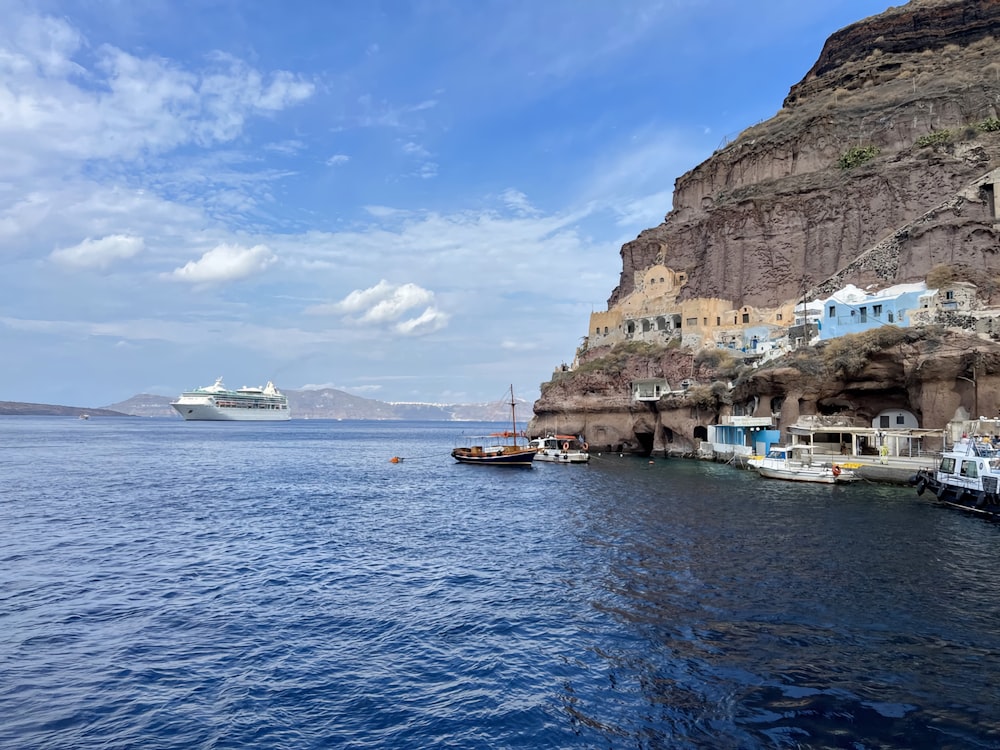 a cruise ship is in the water near a rocky shore