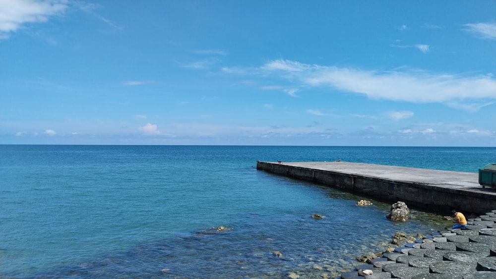 a man sitting on a bench next to a body of water