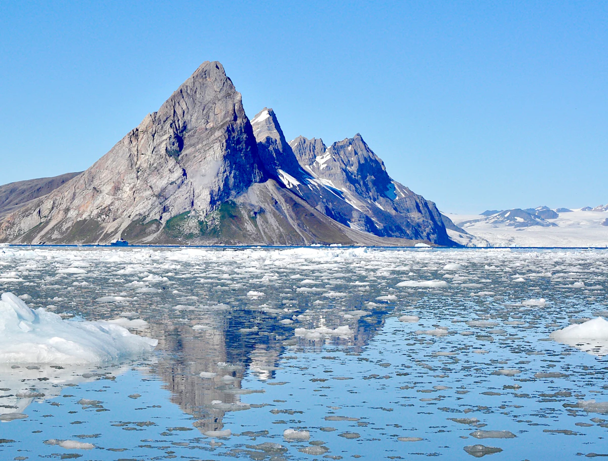 Arctic mountain rising above scattered ice floes in a quiet polar bay