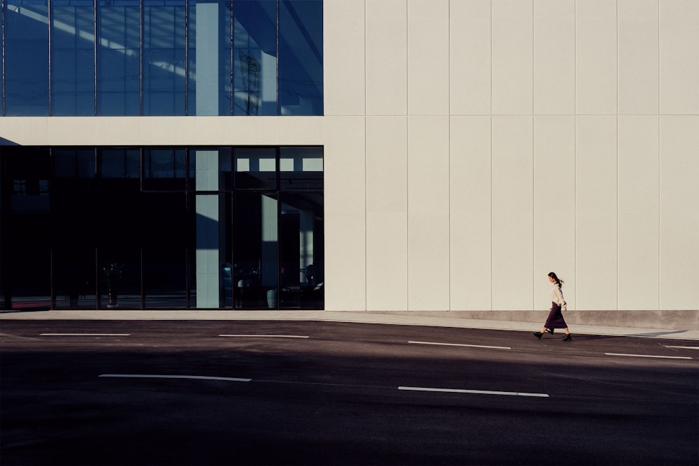 a woman walking down a street past a tall building