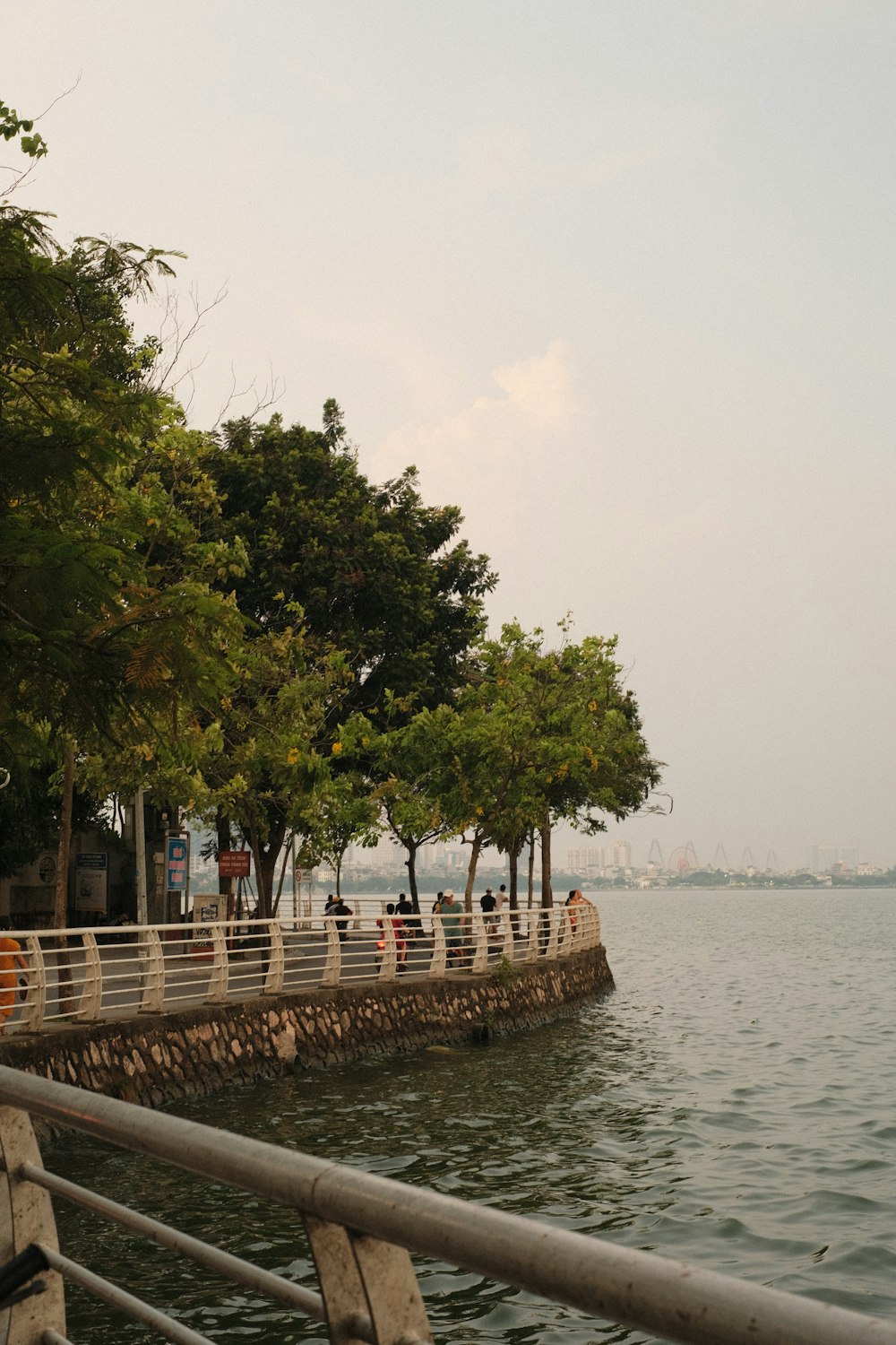 a group of people standing on a pier next to a body of water