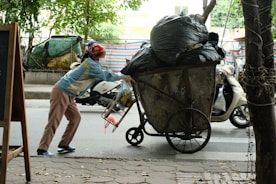 A man pushing a cart full of bags down a street