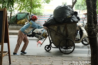 A man pushing a cart full of bags down a street