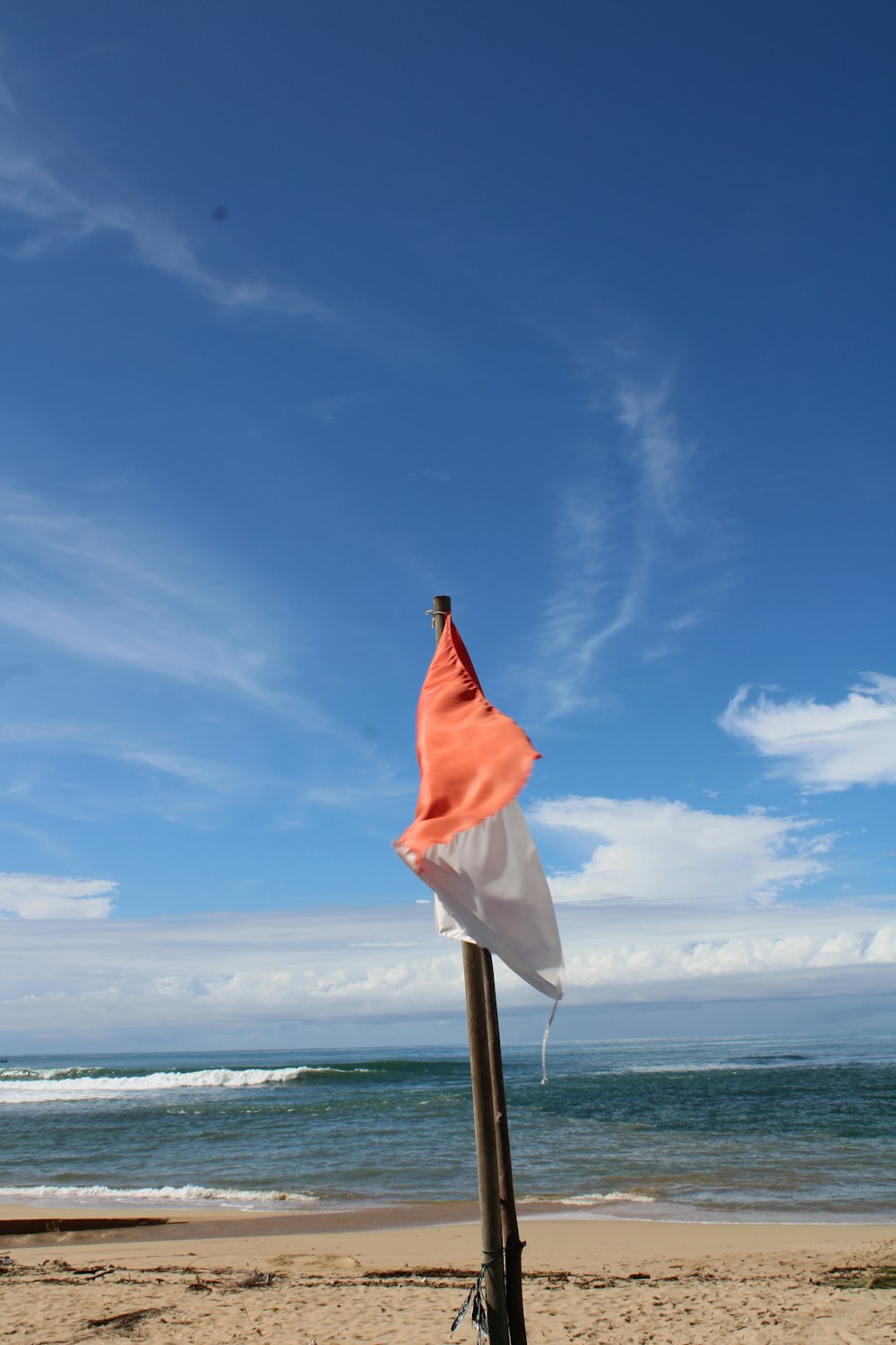 an orange and white flag on a pole on a beach