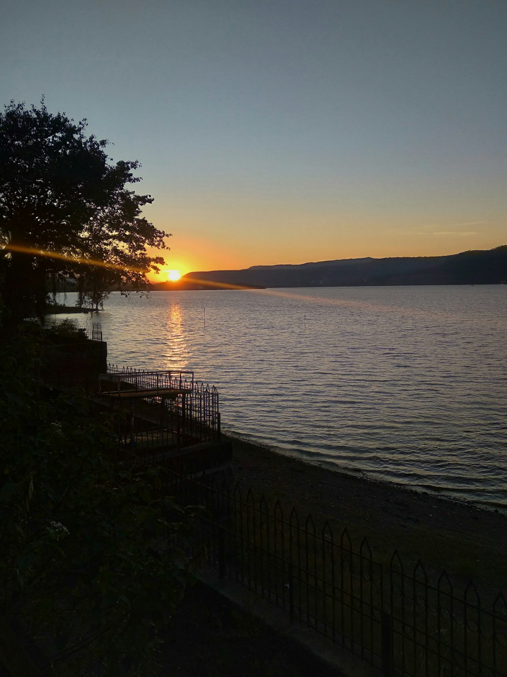 the sun is setting over the water at the beach