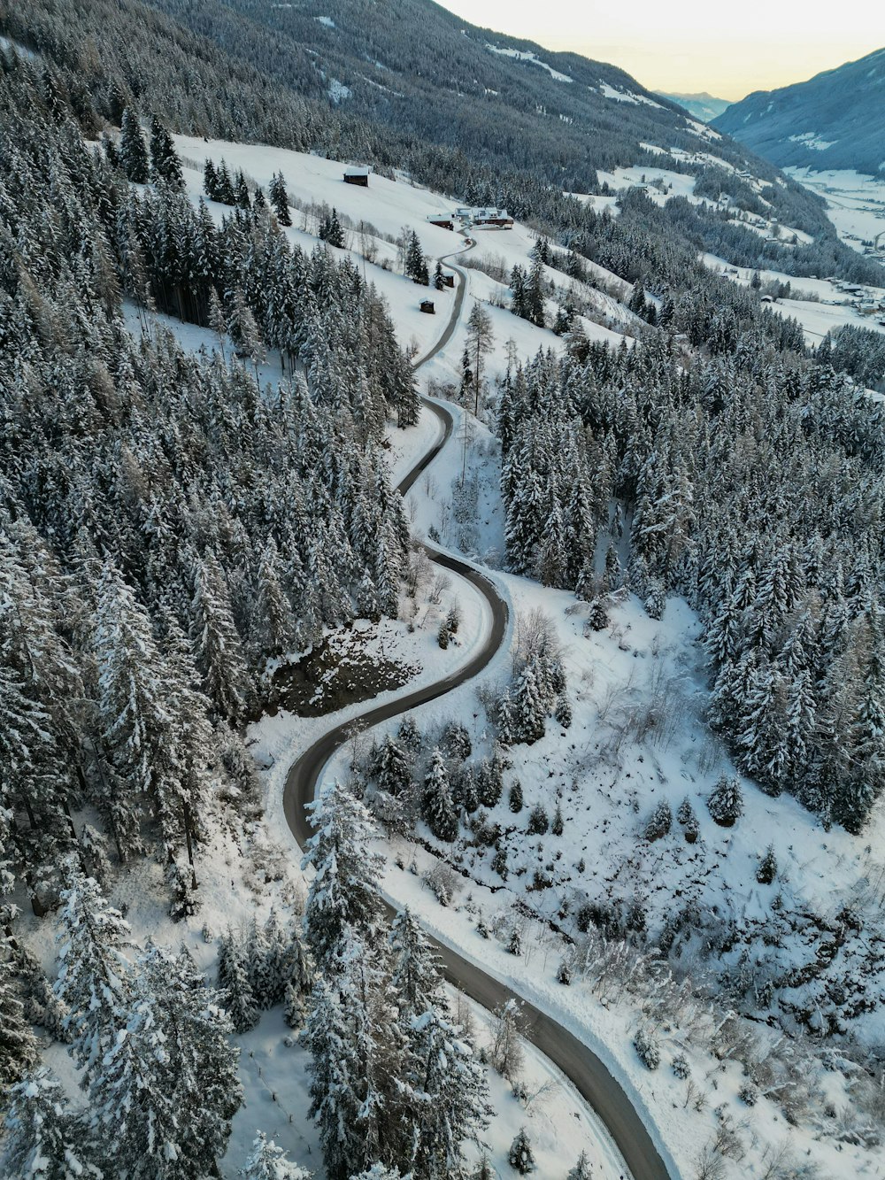 a winding road surrounded by snow covered trees