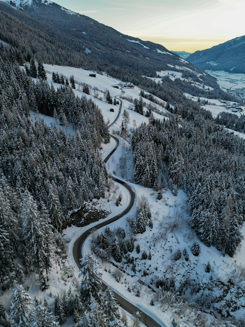 a winding road surrounded by snow covered trees