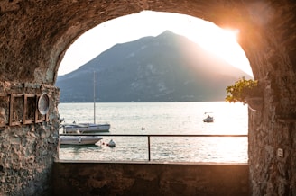 a view of a body of water through a stone tunnel