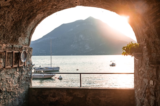 a view of a body of water through a stone tunnel
