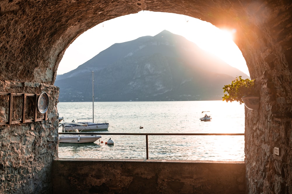 a view of a body of water through a stone tunnel