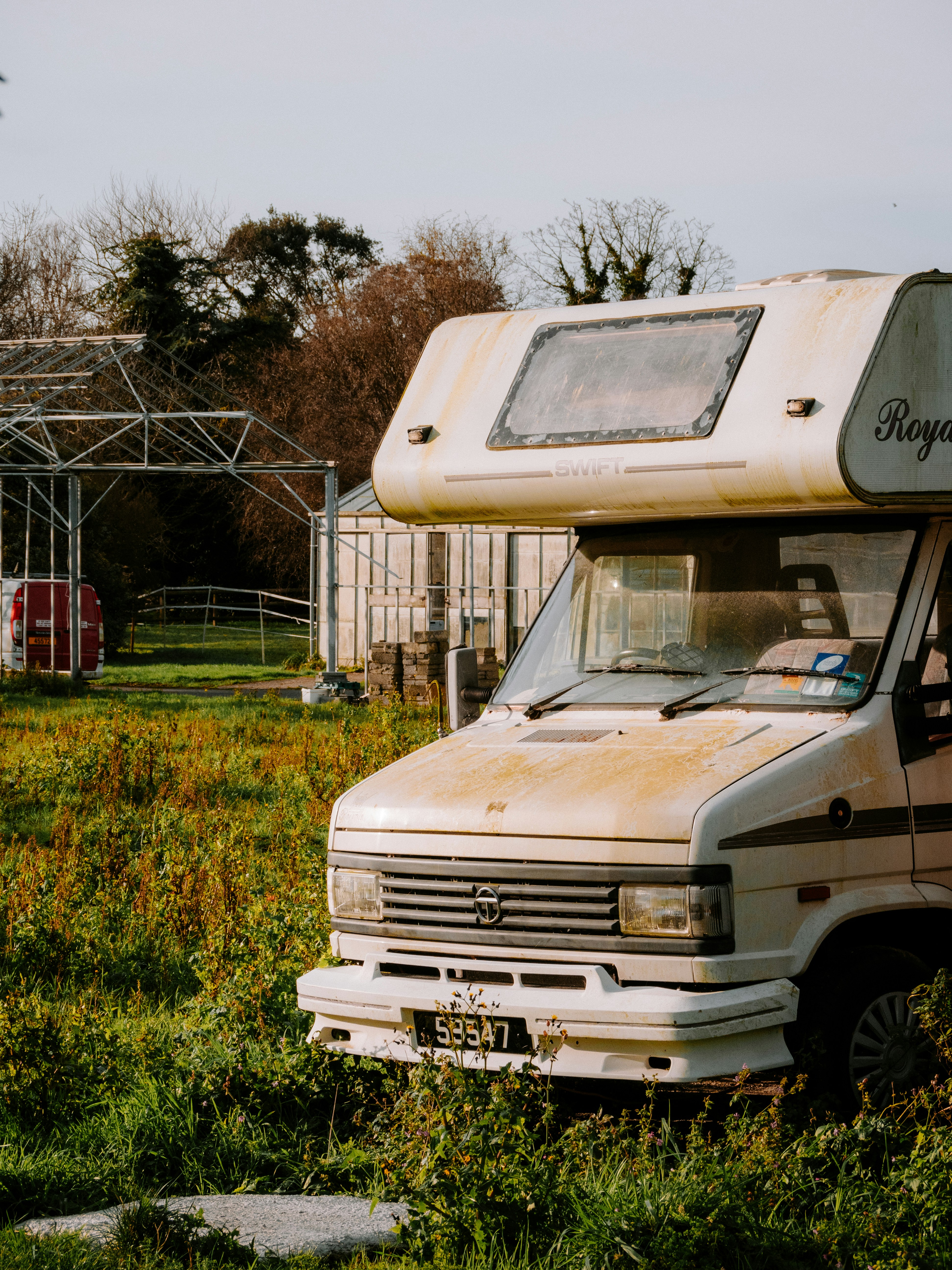 an old camper parked in a field of tall grass