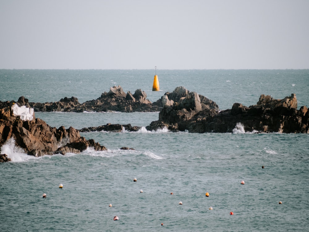 a body of water with rocks and a yellow buoy in the background