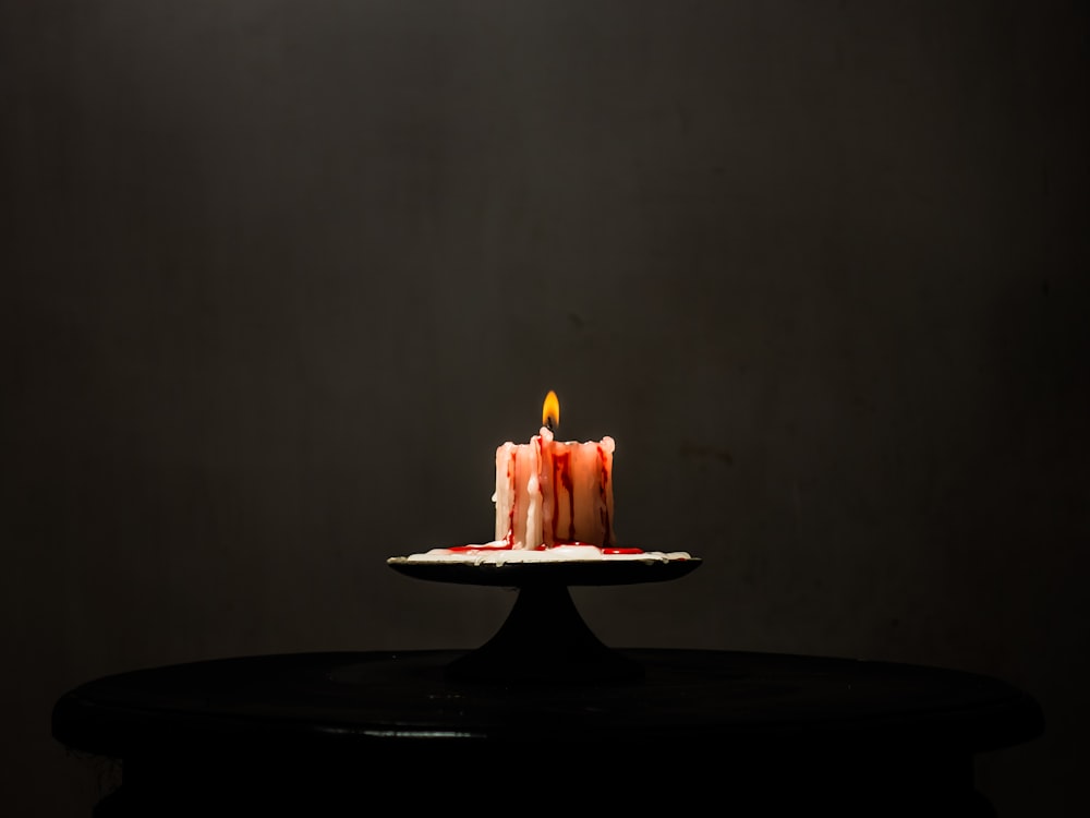 a lit candle sitting on top of a cake plate